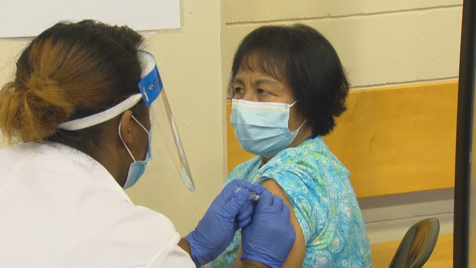 Une travailleuse de la santé injecte le vaccin dans l'épaule d'Anita Quidangen, une employée d'un foyer pour aînés.