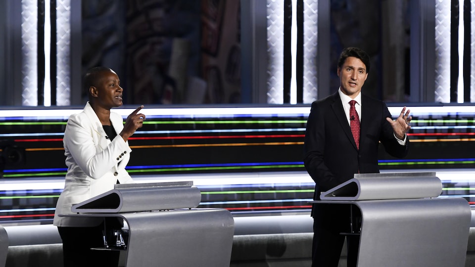 Annamie Paul parle en levant le doigt, Justin Trudeau parle en levant la main.