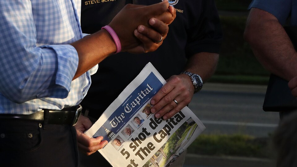 Une homme tient l'édition du 29 juin de la Capital Gazette. En une, on annonce la mort de cinq employés du journal, tués par un tireur le jour précédant.