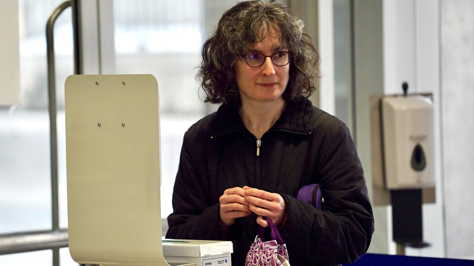 Une femme portant des lunettes regarde au loin. 