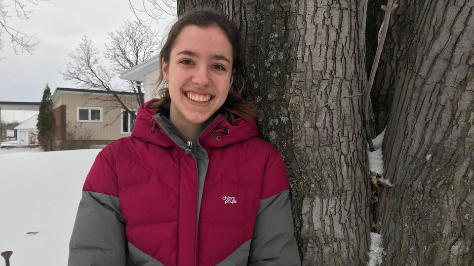 Anne-Catherine Couillard appuyée sur une arbre l'hiver.