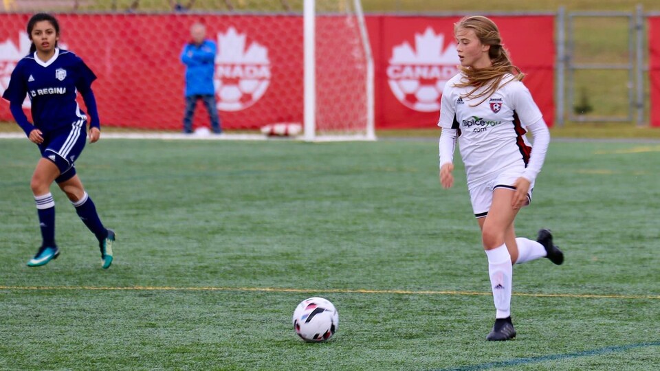 Une jeune femme joue au soccer.