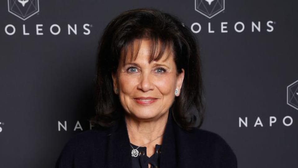 Une femme brune, habillée en noir, sourit.