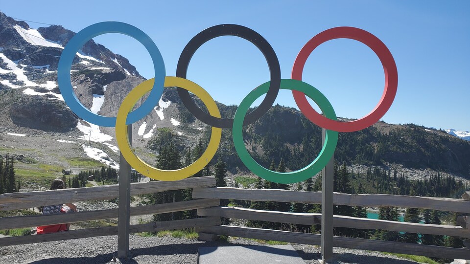 Un podium surmonté d'anneaux olympiques est installé au sommet d'une montagne.