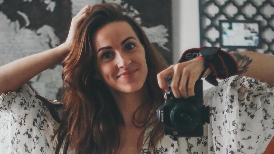 Une jeune femme assise en tailleur se prend en photo dans le miroir.