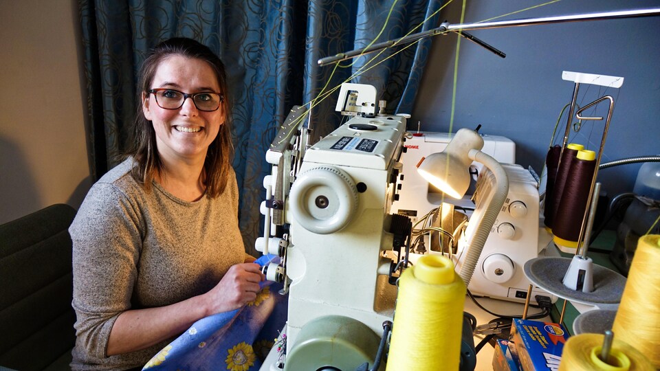 Annie Larocque sourit, assise devant une machine à coudre.