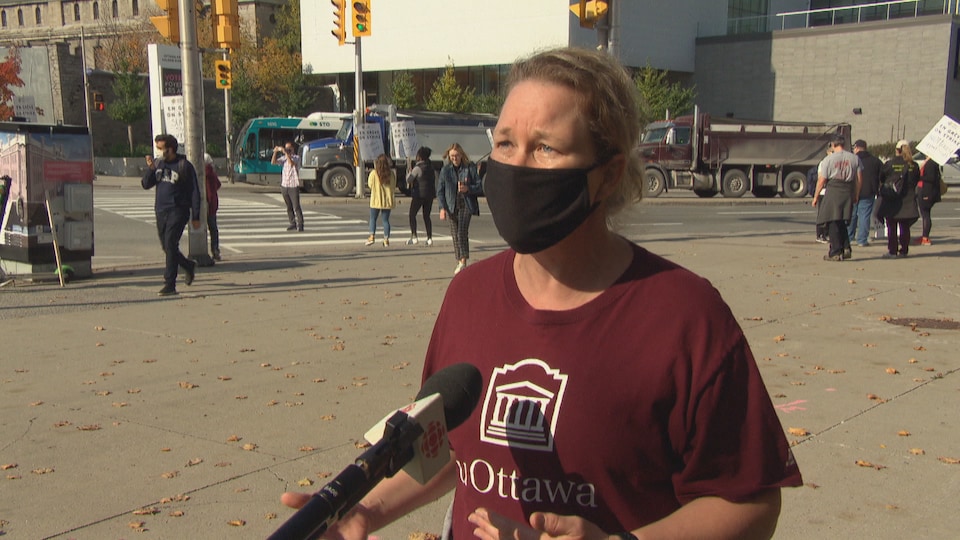 Une femme porte un masque et un chandail de l'Université d'Ottawa. Elle parle au micro de Radio-Canada.