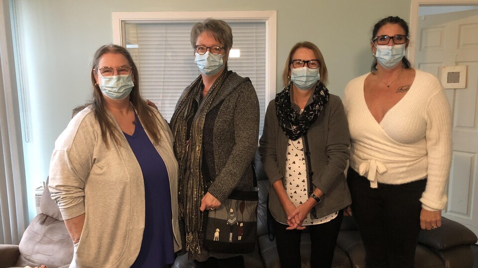 Les quatre femmes regardent la caméra, elles portent un masque.