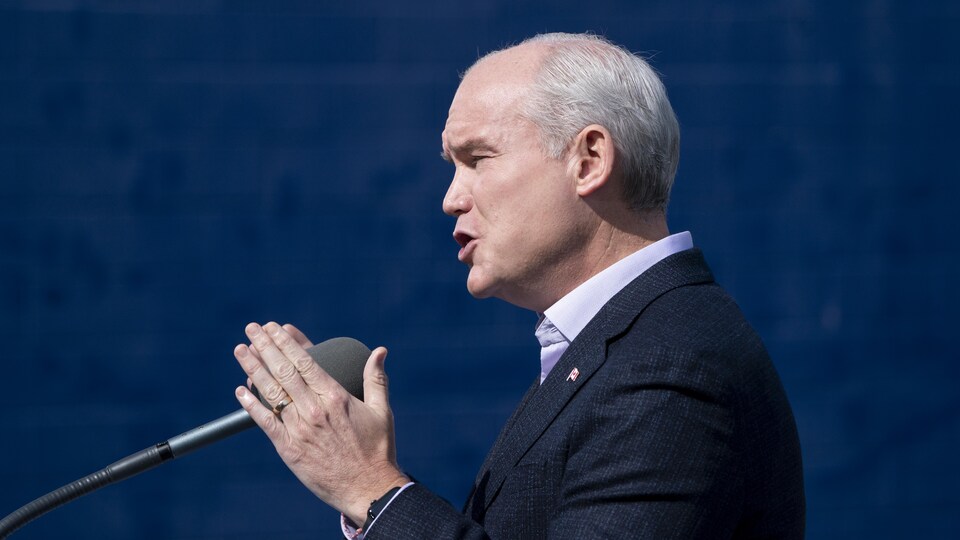 Erin O'Toole, de profil, parle aux médias.