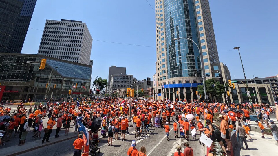 Des centaines de personnes dans une rue portant des chemises orange.