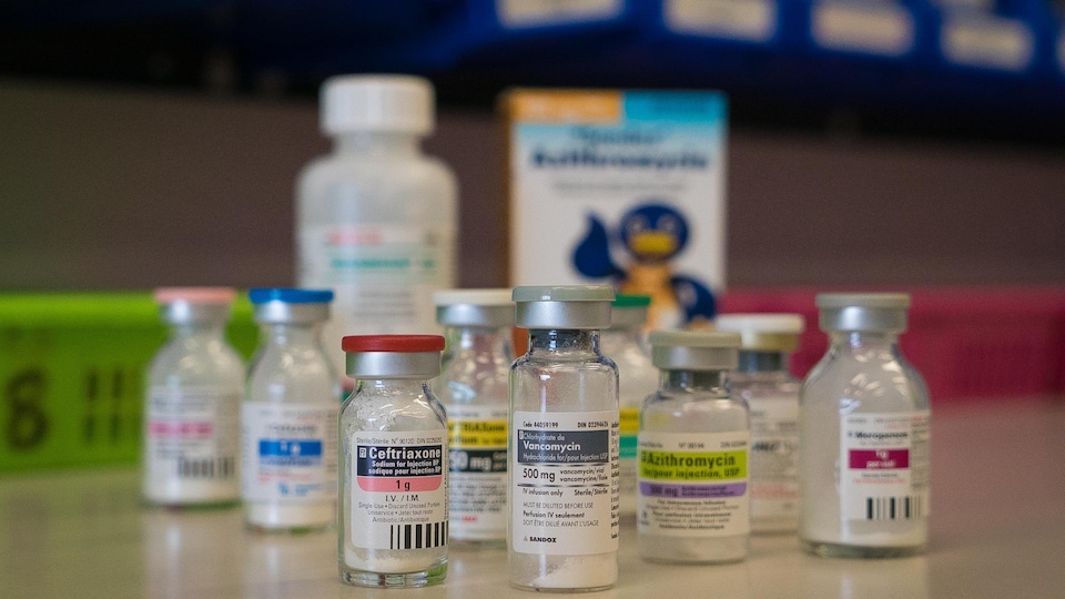 On voit en gros plan plusieurs flacons d'antibiotiques sur un comptoir de la pharmacie d'un hôpital.