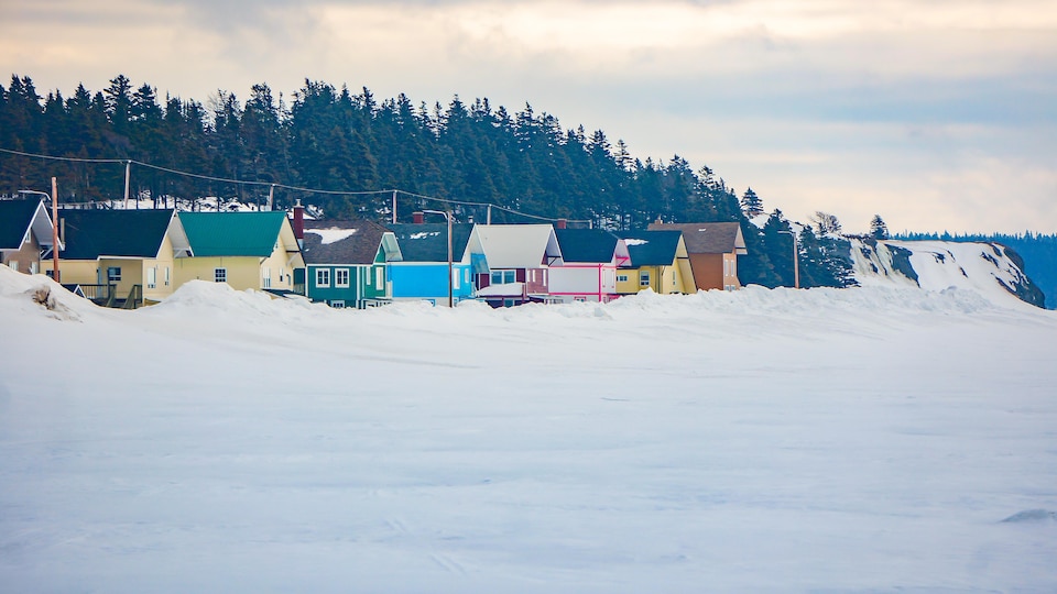 Des maisons sur le bord de la plage couverte de neige à Anticosti.