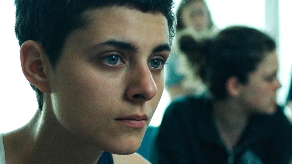 Une jeune femme regarde vers la droite.