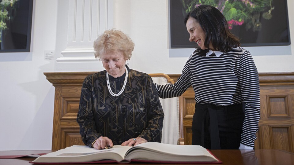 Antonine Maillet devant le livre d’or de la Ville de Montréal, avec à ses côtés Valérie Plante.