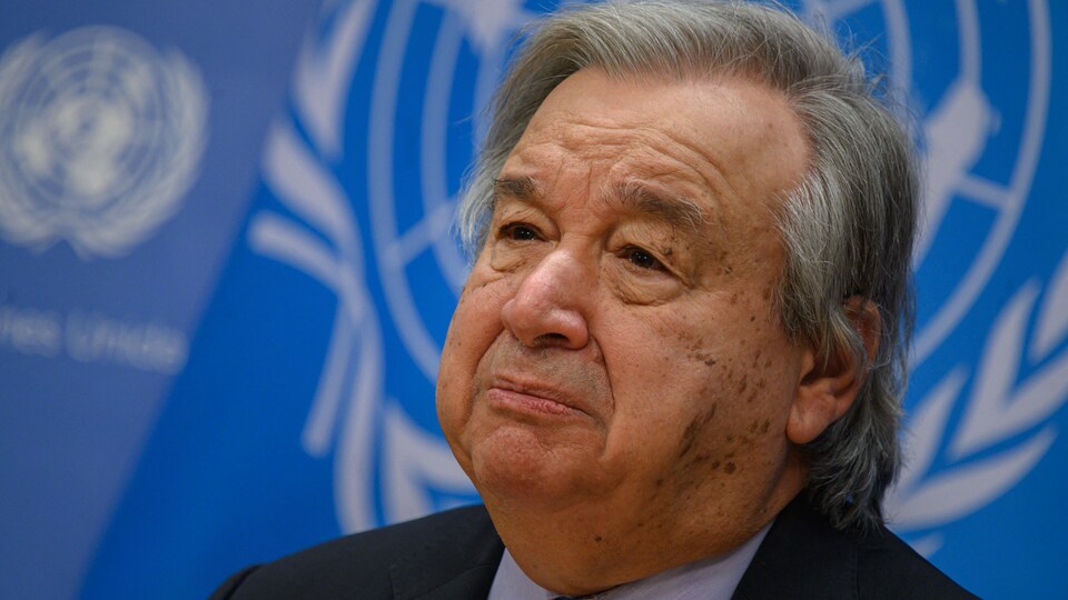 Le visage d'un homme avec en arrière-plan le drapeau de l’Organisation des Nations unies.