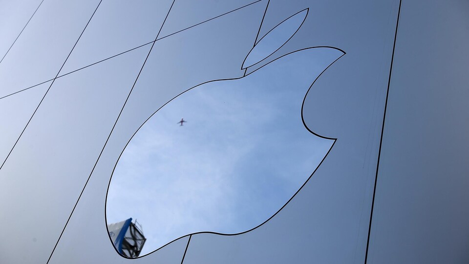 Le logo d'Apple en forme de pomme croquée sur un bâtiment vitré.