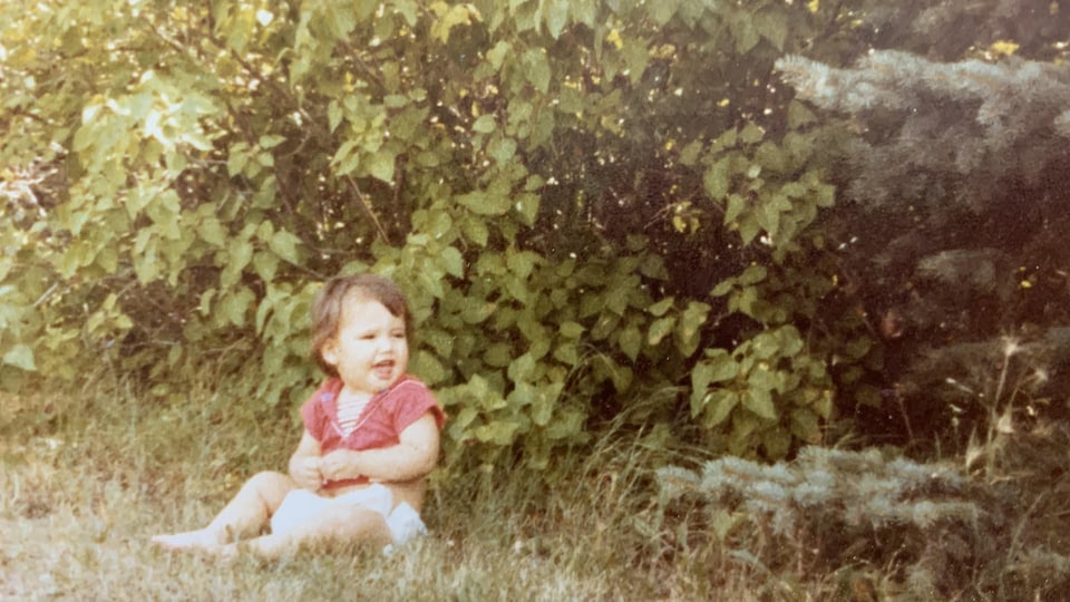 April Eve Wiberg, bébé, assise dans le gazon.