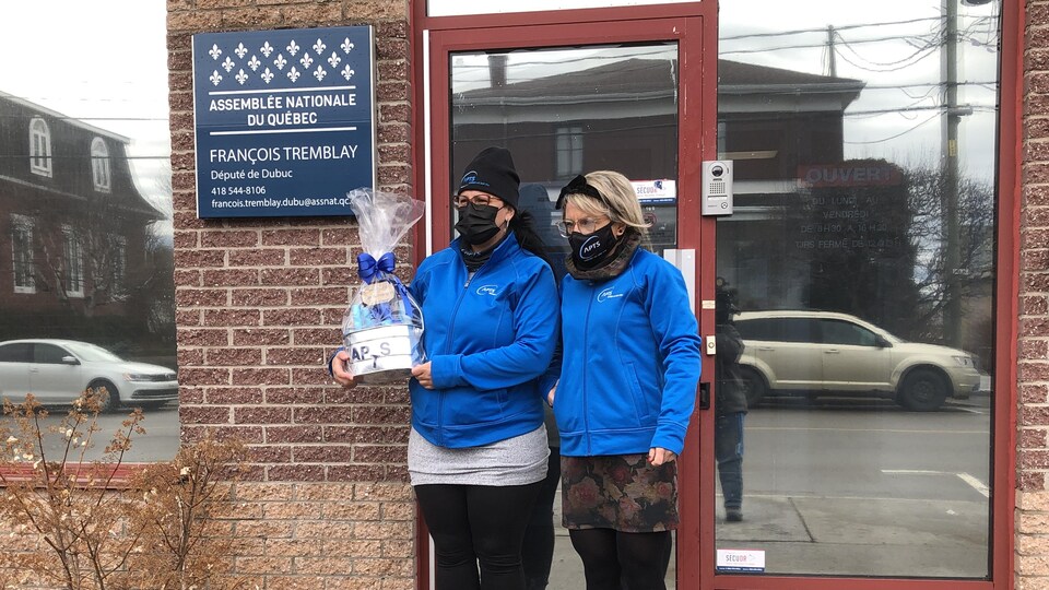 Deux femmes se trouvent devant le bureau du député de Dubuc, François Tremblay. Elles portent un panier.