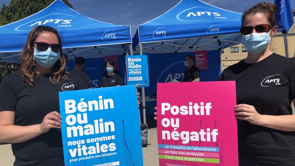Deux syndiqués tiennent des pancartes.