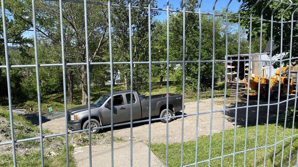 Une camionnette vue sur un chantier à travers une clôture.