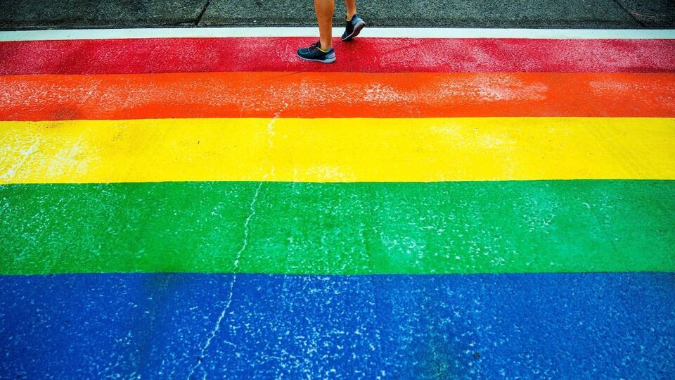 Une personne traverse un passage piéton arc-en-ciel de Seatlle.