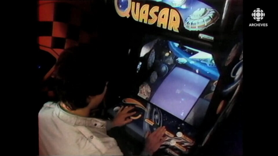Un jeune homme joue au jeu vidéo Quasar dans une arcade.