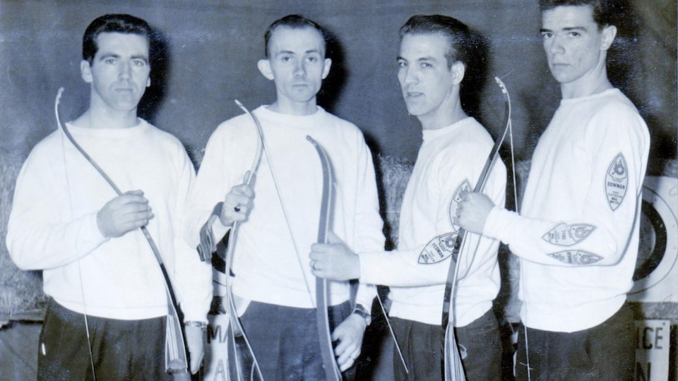 Une photo en noir et blanc de quatre hommes avec leur arc.