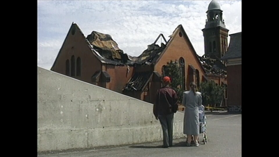 Deux personnes regardent les ruines d'une église.