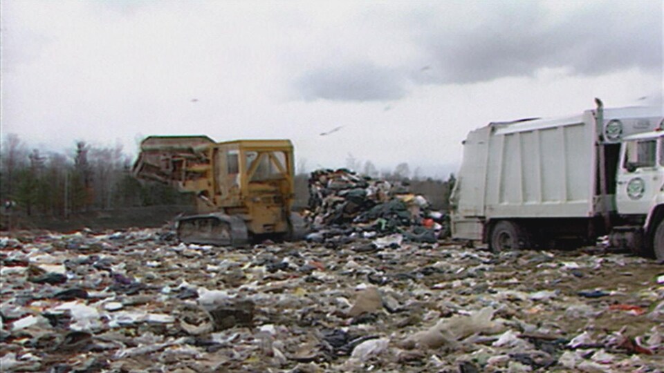 Un camion et une pelle mécanique sont à l'oeuvre dans sur un site d'enfouissement des déchets.