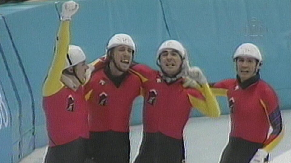 Les quatre patineurs de l'équipe de relais célèbrent sur la glace après leur victoire.