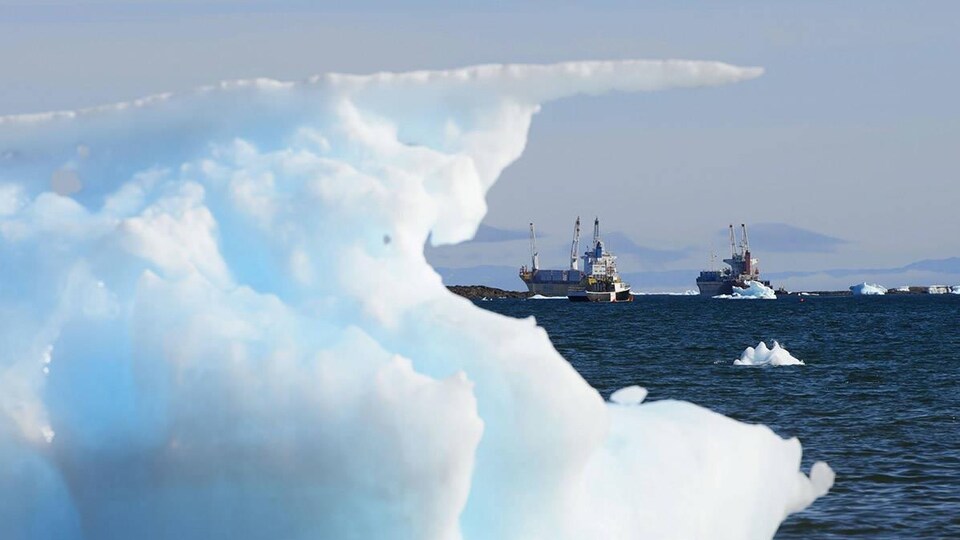 Deux navires dans la baie derrière un iceberg.