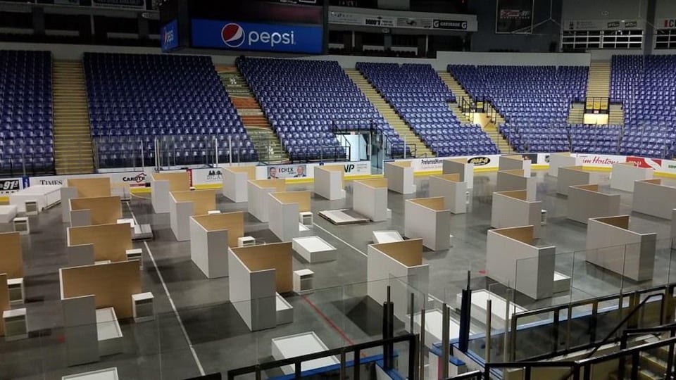 Le centre de l'aréna est occupé par des installations en bois constituées de panneaux de séparation, de lits et de meubles de chevet.