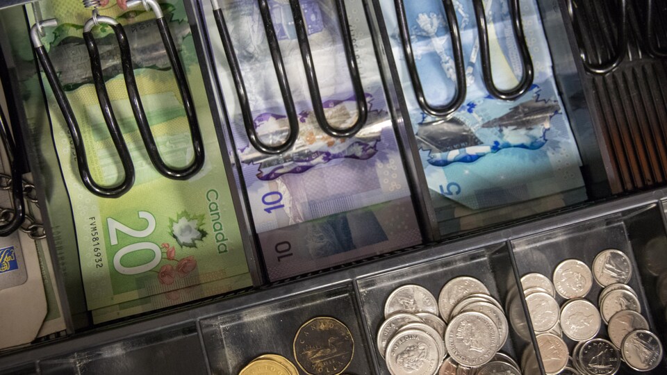 Vue de l'intérieur d'une caisse enregistreuse, remplie de billets et de pièces de monnaie.