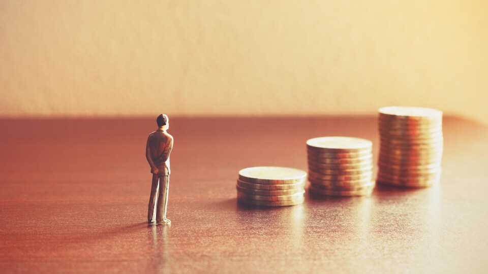 Une petite figurine d'un homme se tient devant trois piles de pièces de monnaie de plus en plus grande.