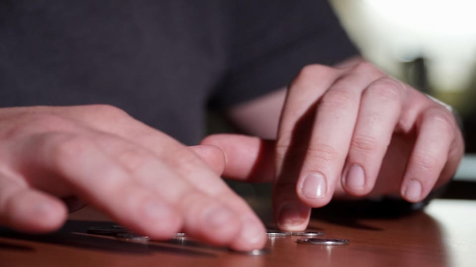 Des mains qui comptent de la monnaie sur la table.