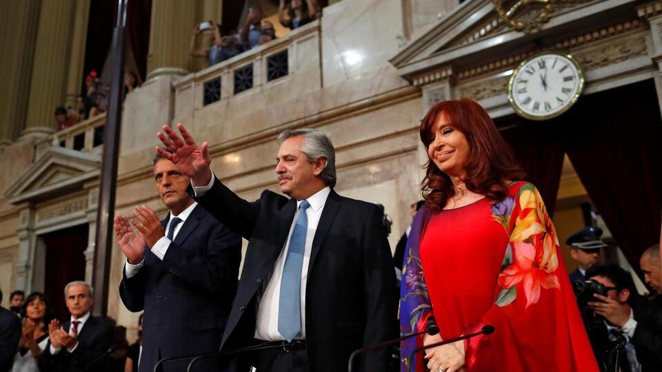 Le président argentin Alberto Fernandez tend la main vers le ciel. La  vice-présidente Cristina Fernandez de Kirchner est à sa gauche et sourit. 