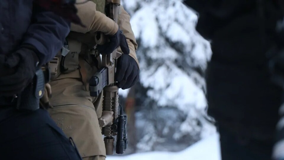Un agent tient un fusil d'assaut.