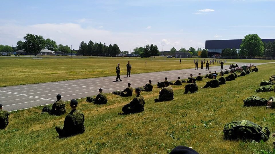 Des recrues assises au sol à deux mètres de distance, respectant la distanciation physique.