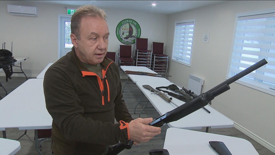 Un homme tient une arme dans une salle.
