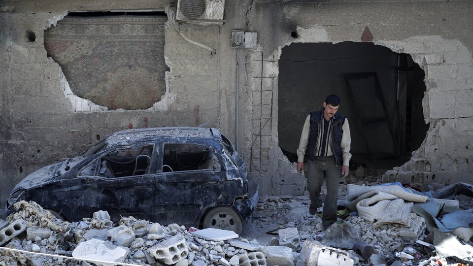 Un homme marche dans les décombres d'une ville en ruines.