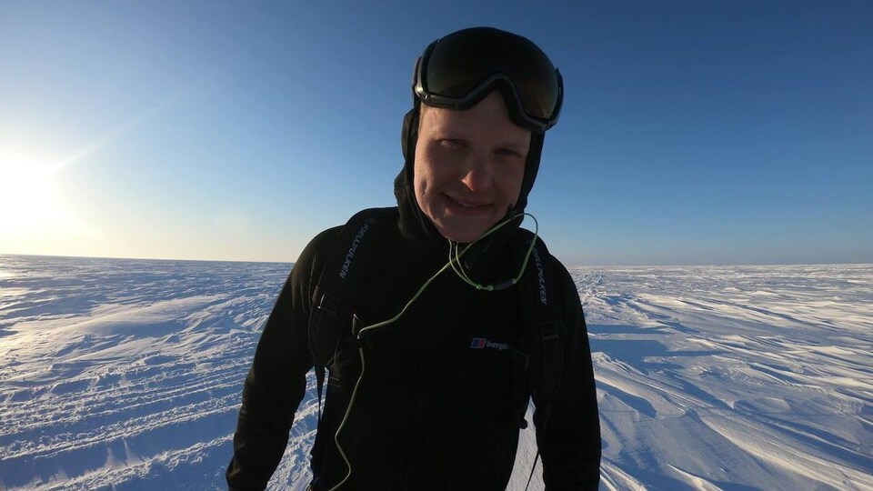 Un homme avec des lunettes de ski debout dans la neige.