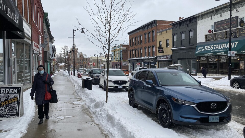 Une femme masquée marche sur le trottoir, dans le ville de Arnprior, située dans le comté de Renfrew.