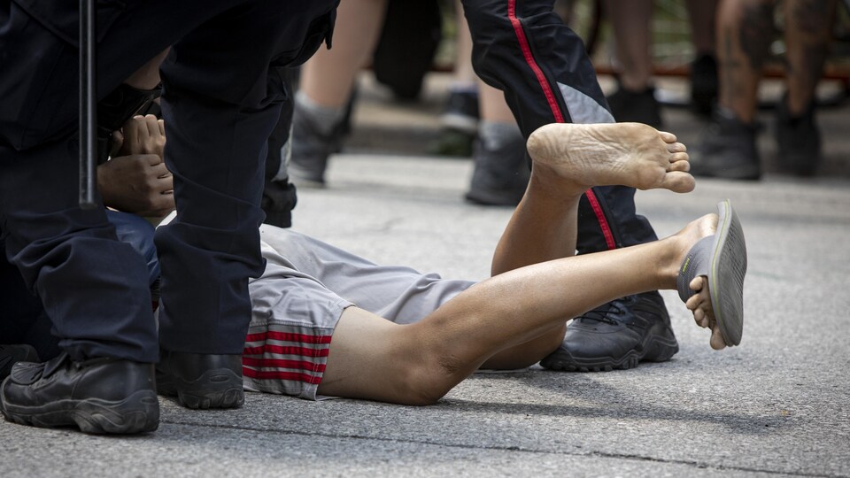 Un homme maintenu au sol par des policiers.