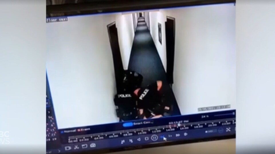 Capture d'écran d'une vidéo de caméra de surveillance montrant trois policiers tentant de maîtriser un homme.