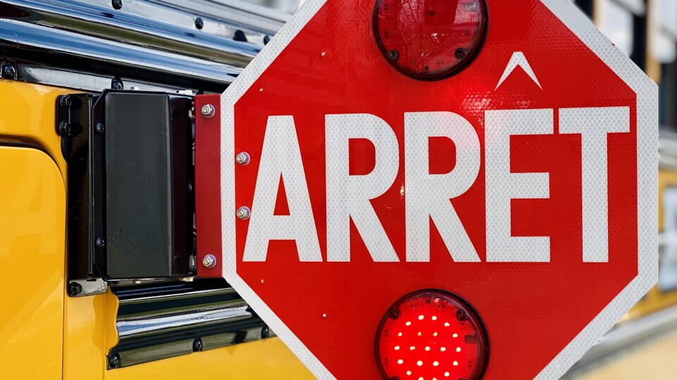 Gros plan sur une pancarte d'arrêt d'un autobus scolaire déployée.