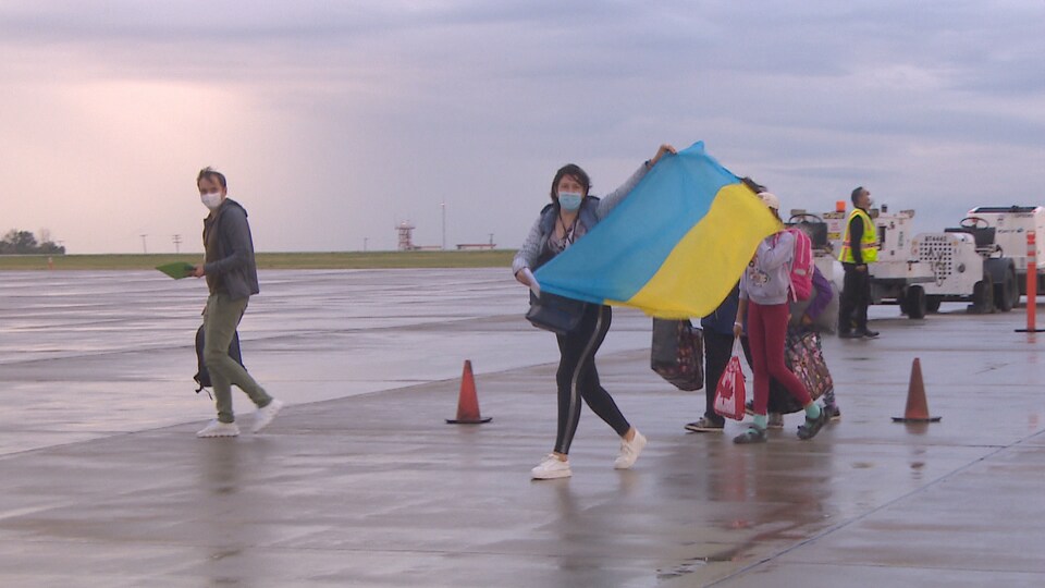 Des gens sur un tarmac avec un drapeau jaune et bleu.