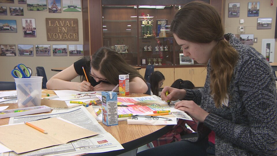 Deux élèves sont concentrées à dessiner des oeuvres pour l'oeuvre d'art publique qui sera présentée au parc de la Confédération de Regina. 