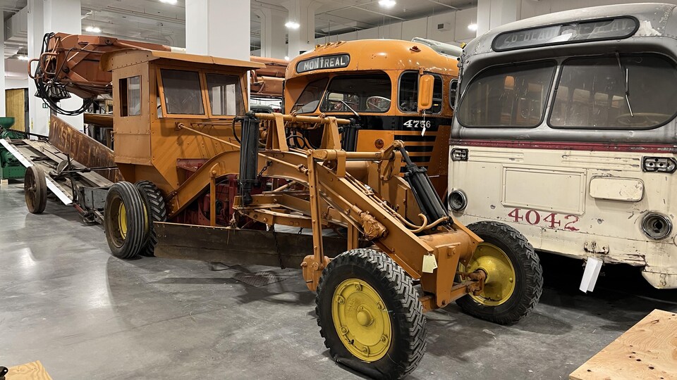 D'anciens véhicules agricoles ou de transport collectif sont rassemblés dans un entrepôt.