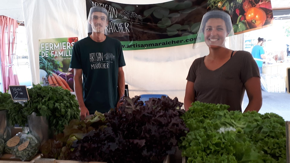 Deux producteurs posent devant leurs légumes avec une visière.