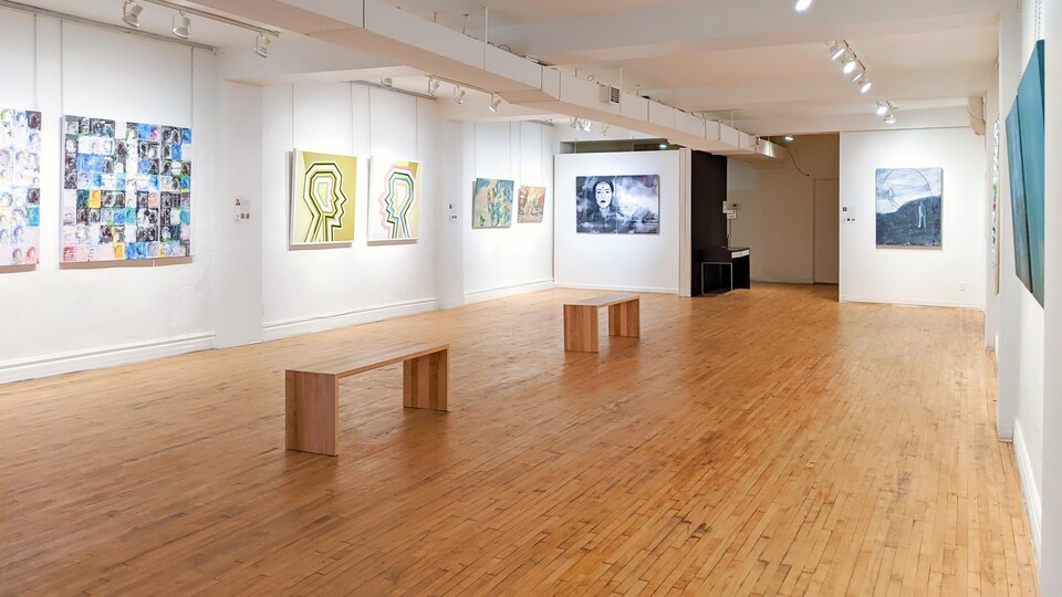 Une salles d'expositions avec huit oeuvres et un plancher de bois franc. 
